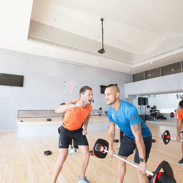 Trainer motivating trainee performing dead-lift exercise