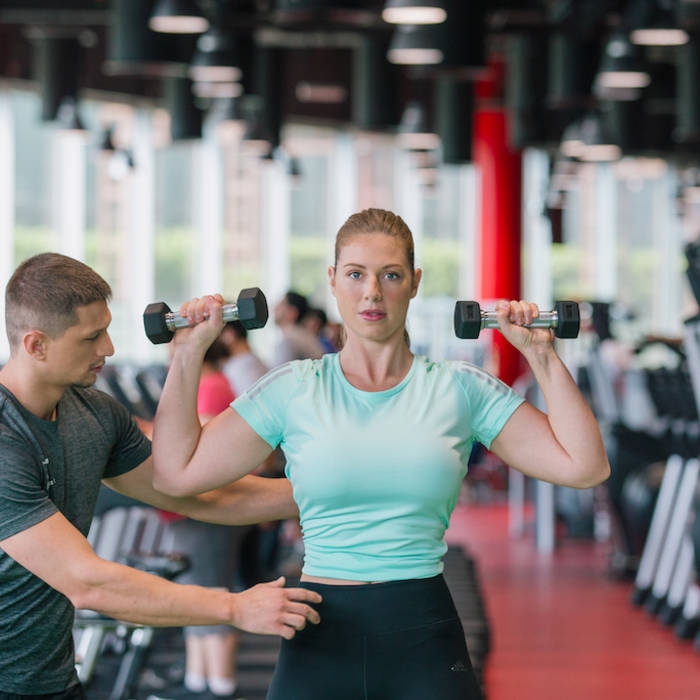 Personal trainer coaching on shoulder dumbbell lift-up