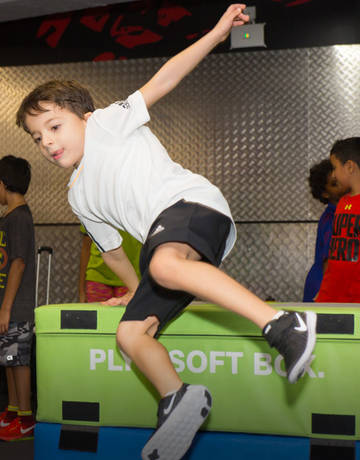 Kid jumping over an obstacle in a Xfit class